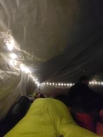 inside of a tent with string lights and sleeping bags