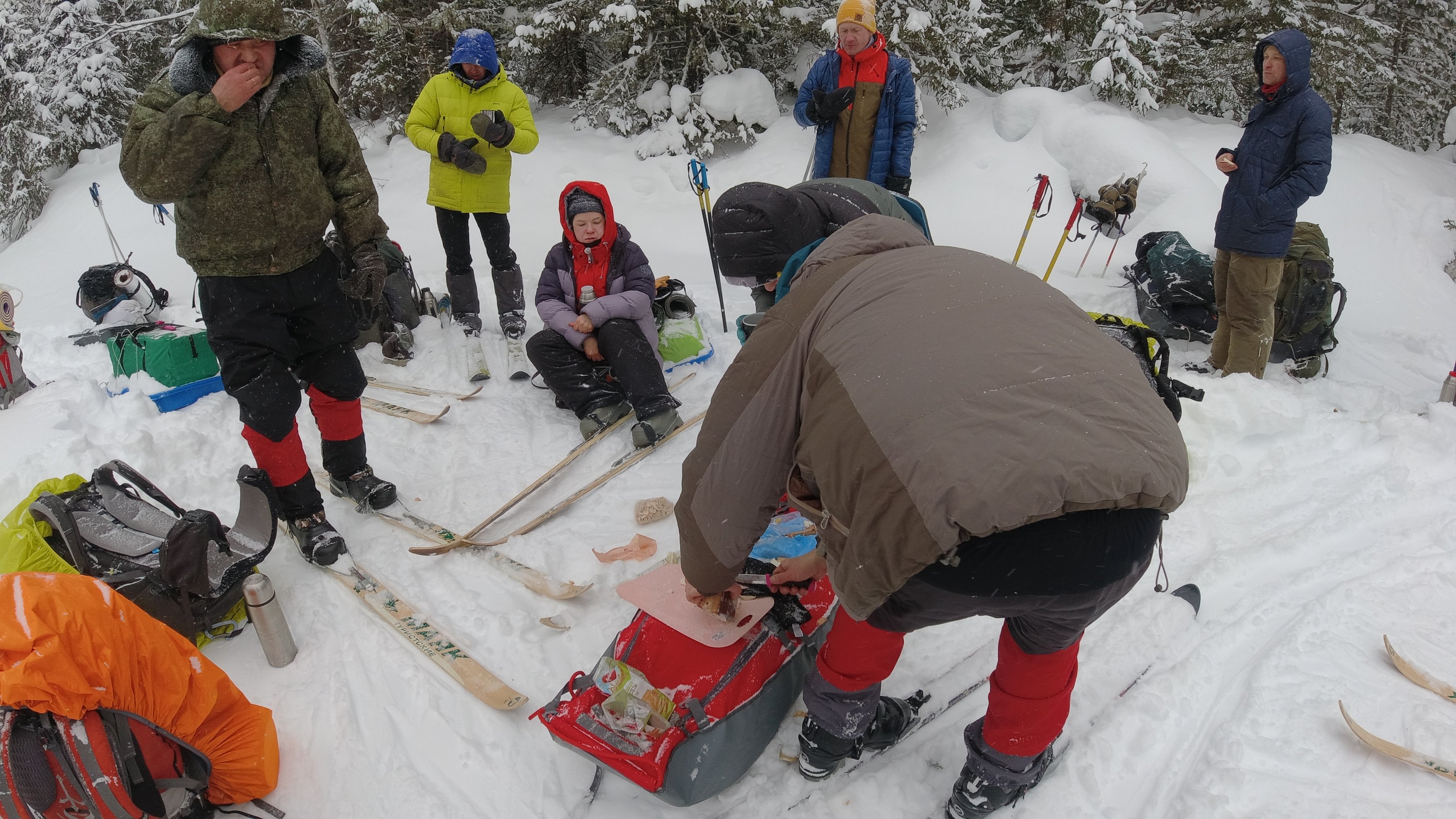 Grupo de esquiadores a preparar comida e equipamento na neve