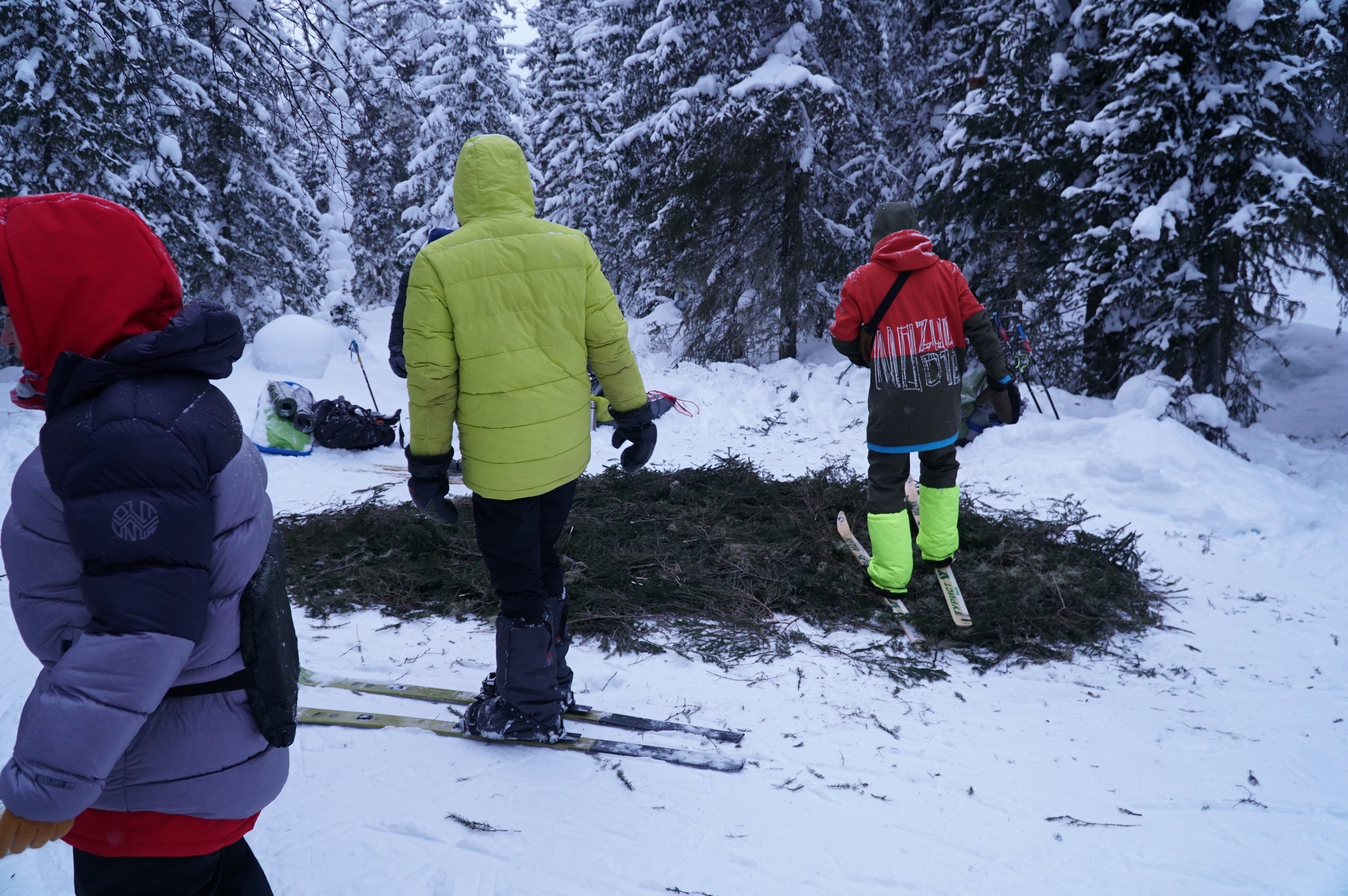 três pessoas com equipamento de inverno em pé na neve