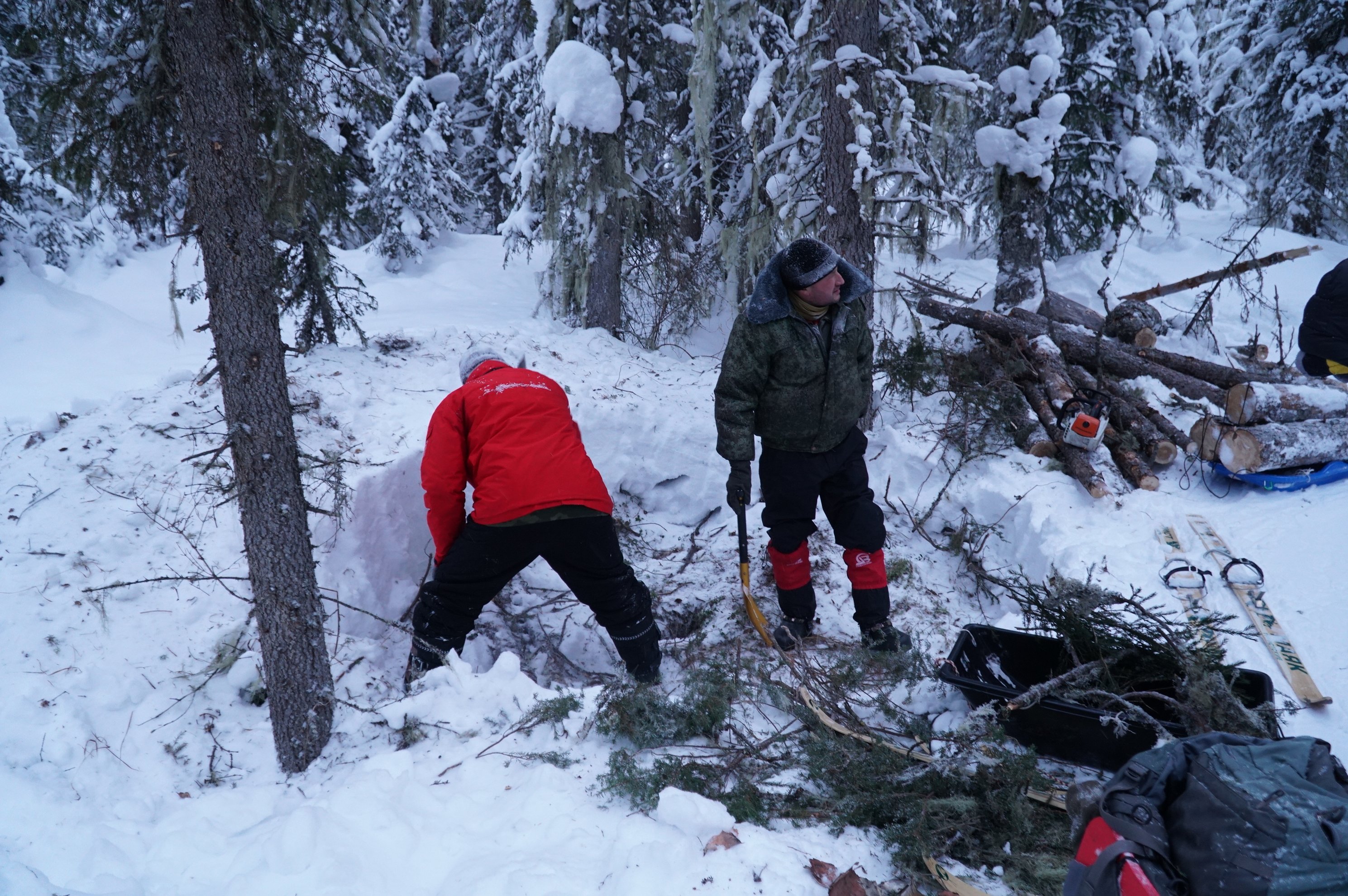 duas pessoas a preparar um acampamento numa floresta nevada