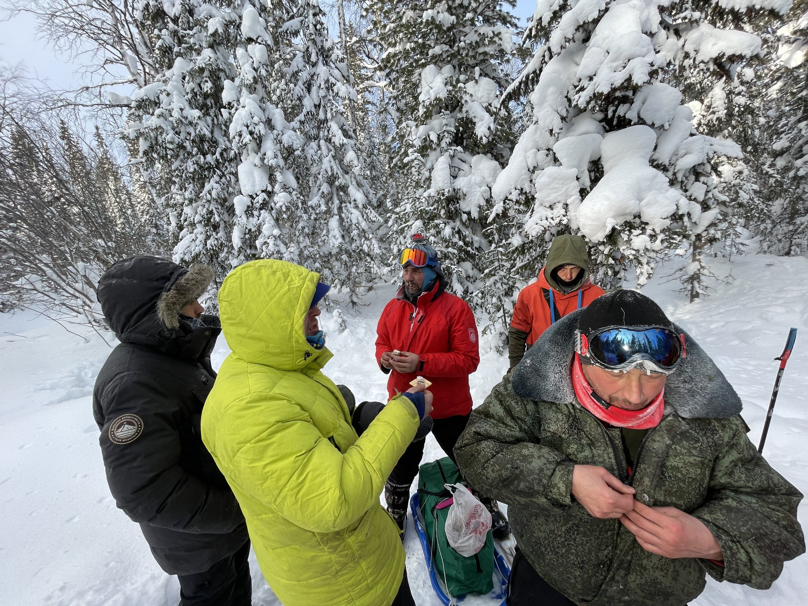 grupo de quatro pessoas com equipamento de inverno a comer e a conversar
