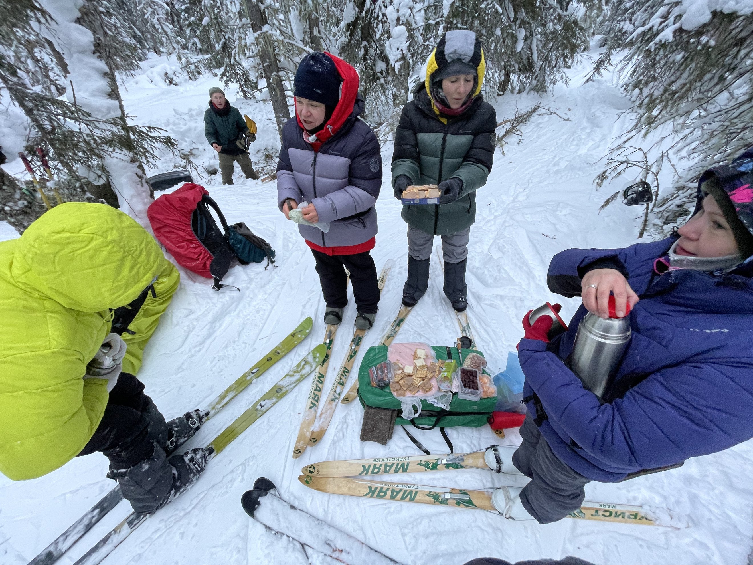 grupo de esquiadores a comer de um saco verde na neve