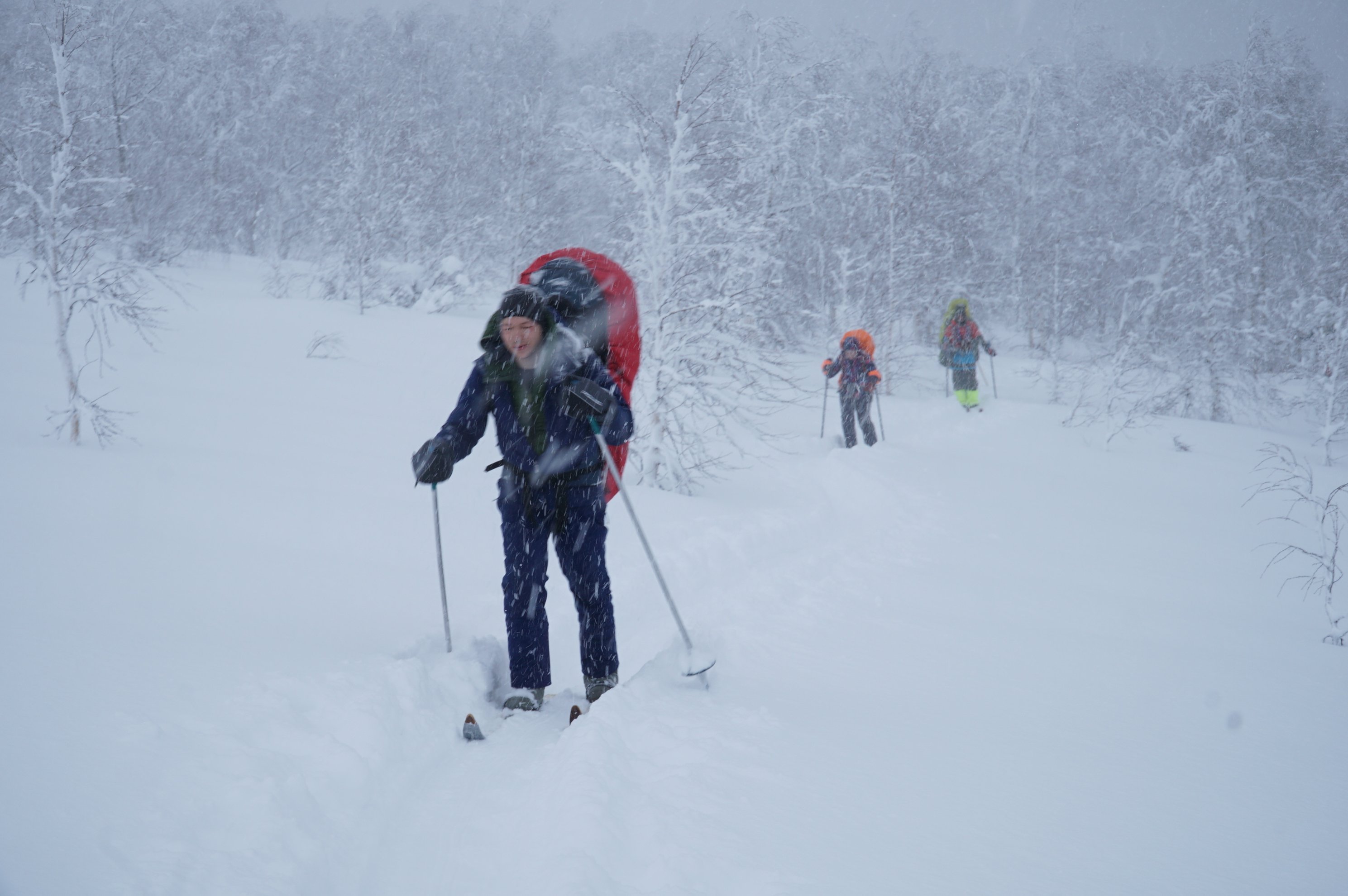 Three skiers moving through a snowstorm toward the camera