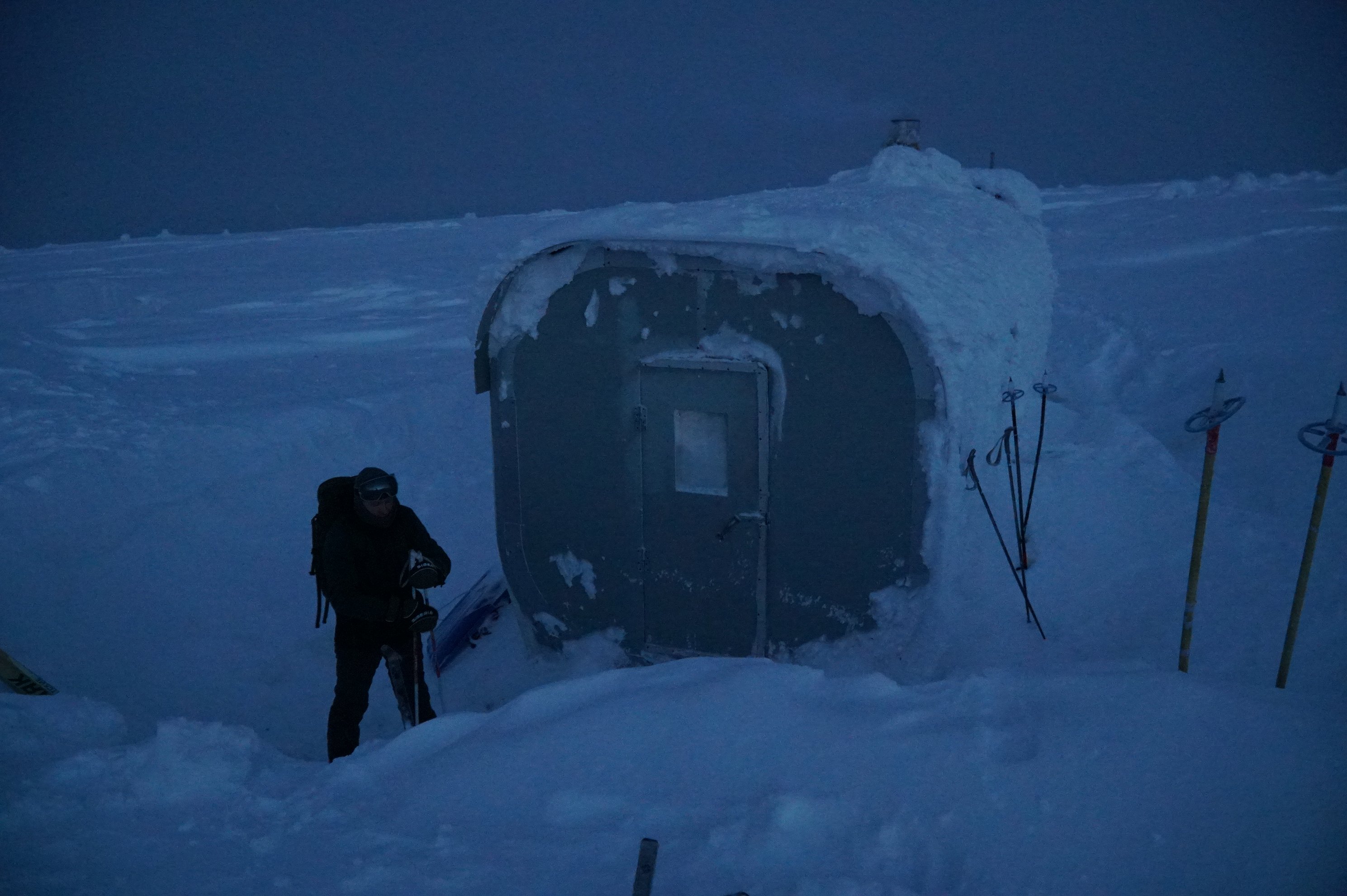 skier standing outside snow-covered shelter