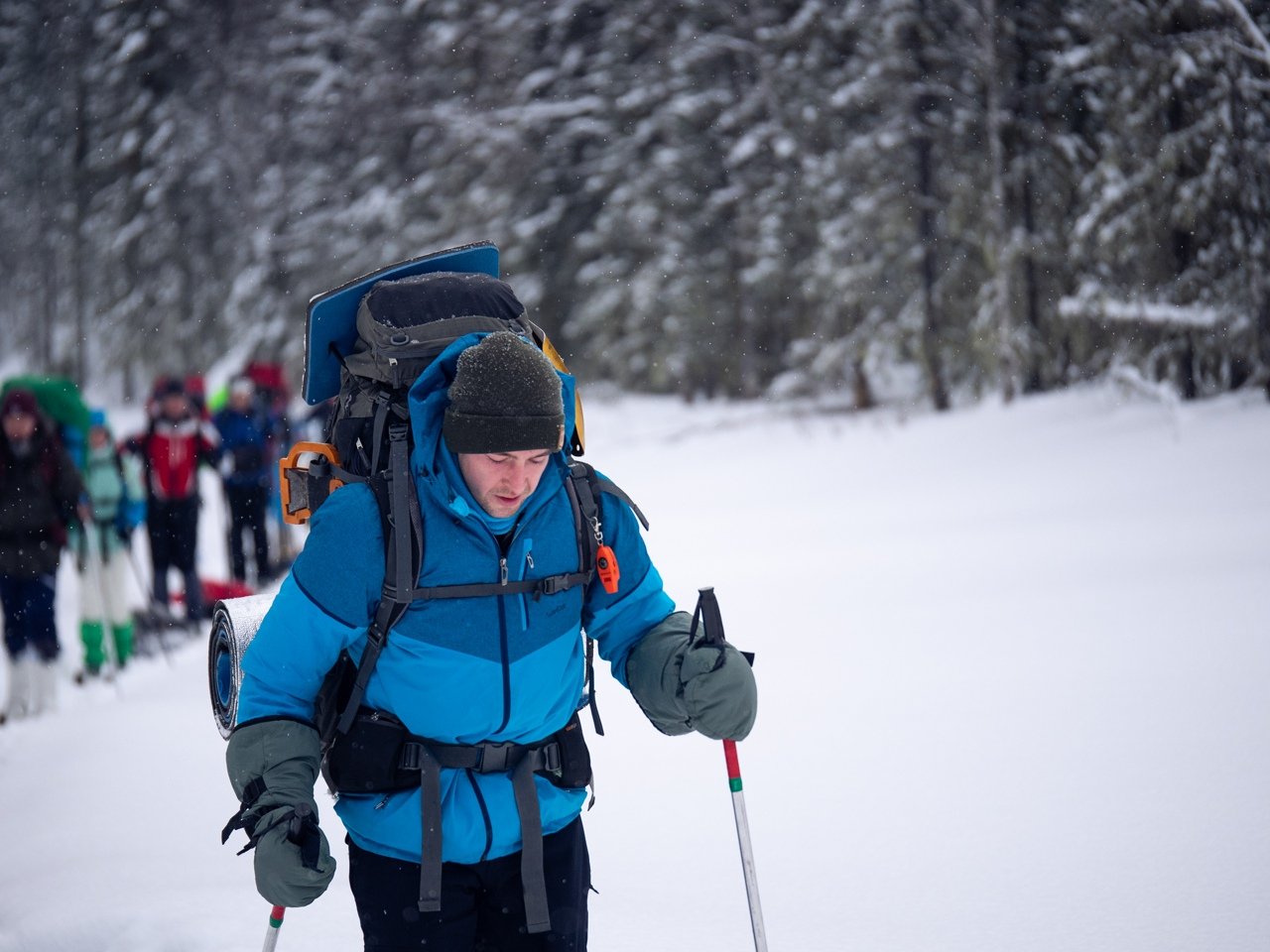 Close up of Sergey skiing with a large backpack and poles