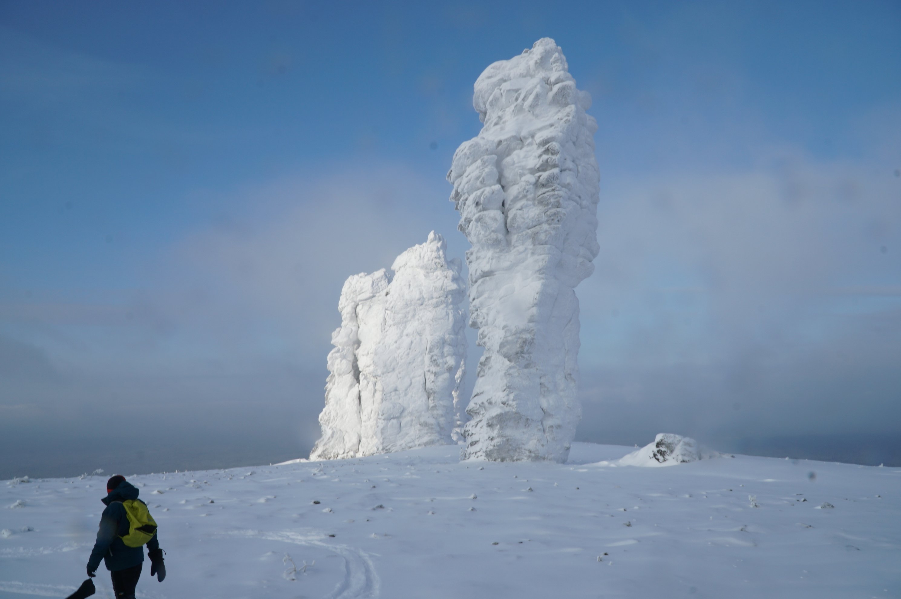 person on skis facing two snow-covered rock pillars