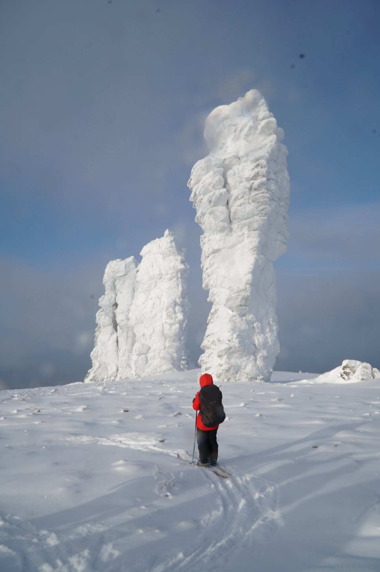 person on skis facing snow-covered rock pillars