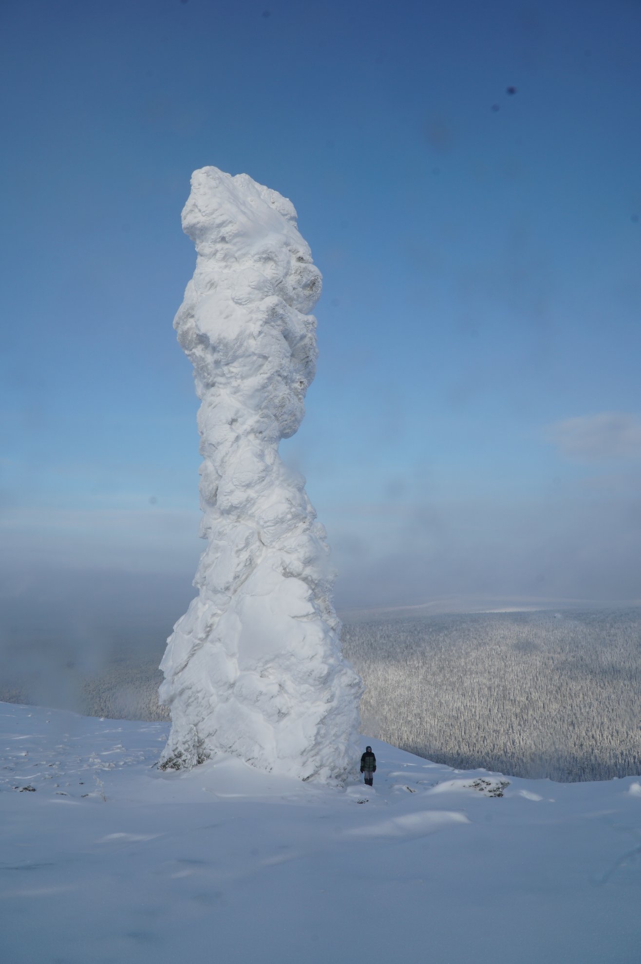 snow covered rock pillar with person standing nearby