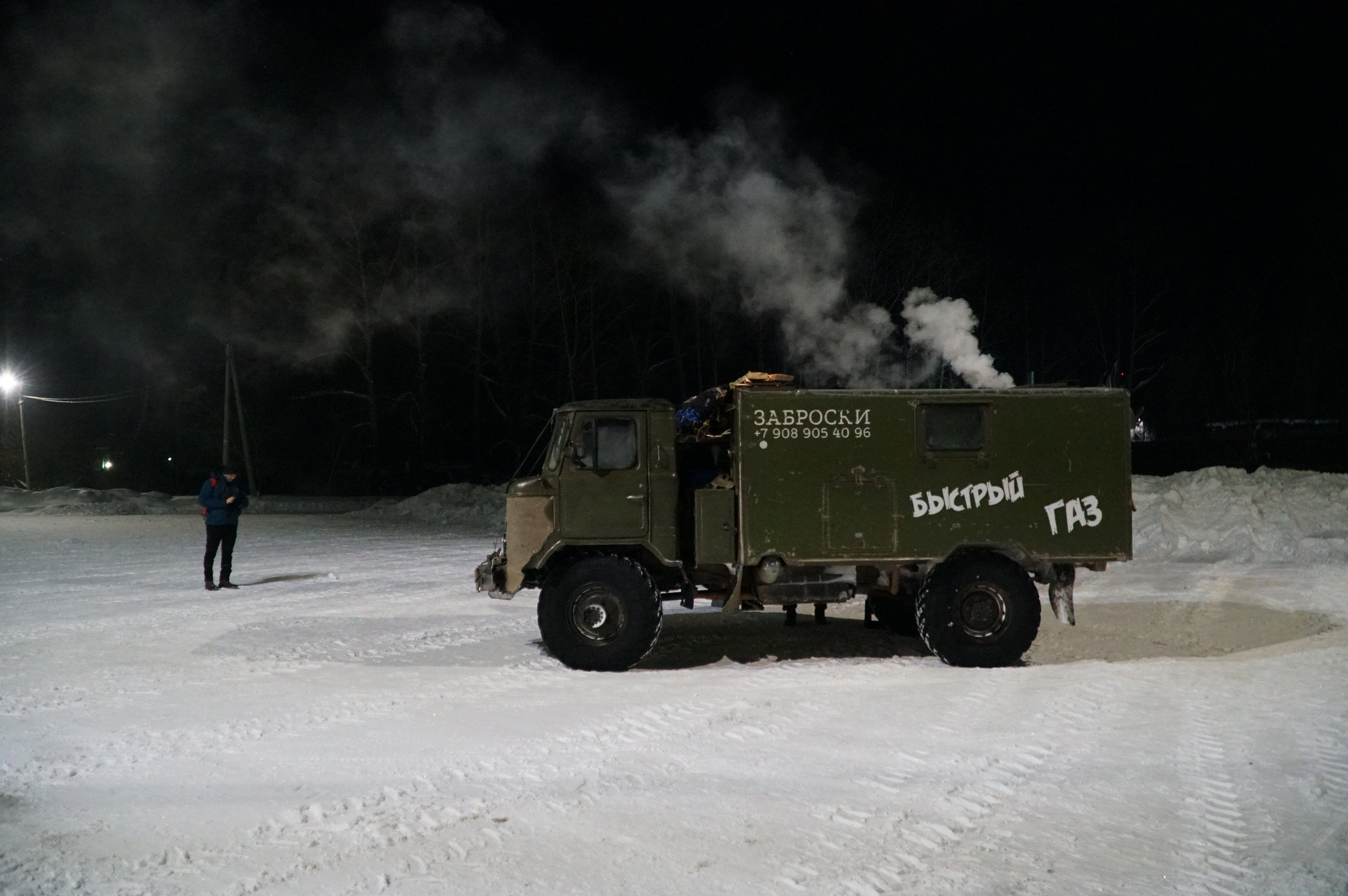 olive green fuel truck parked on snow at night