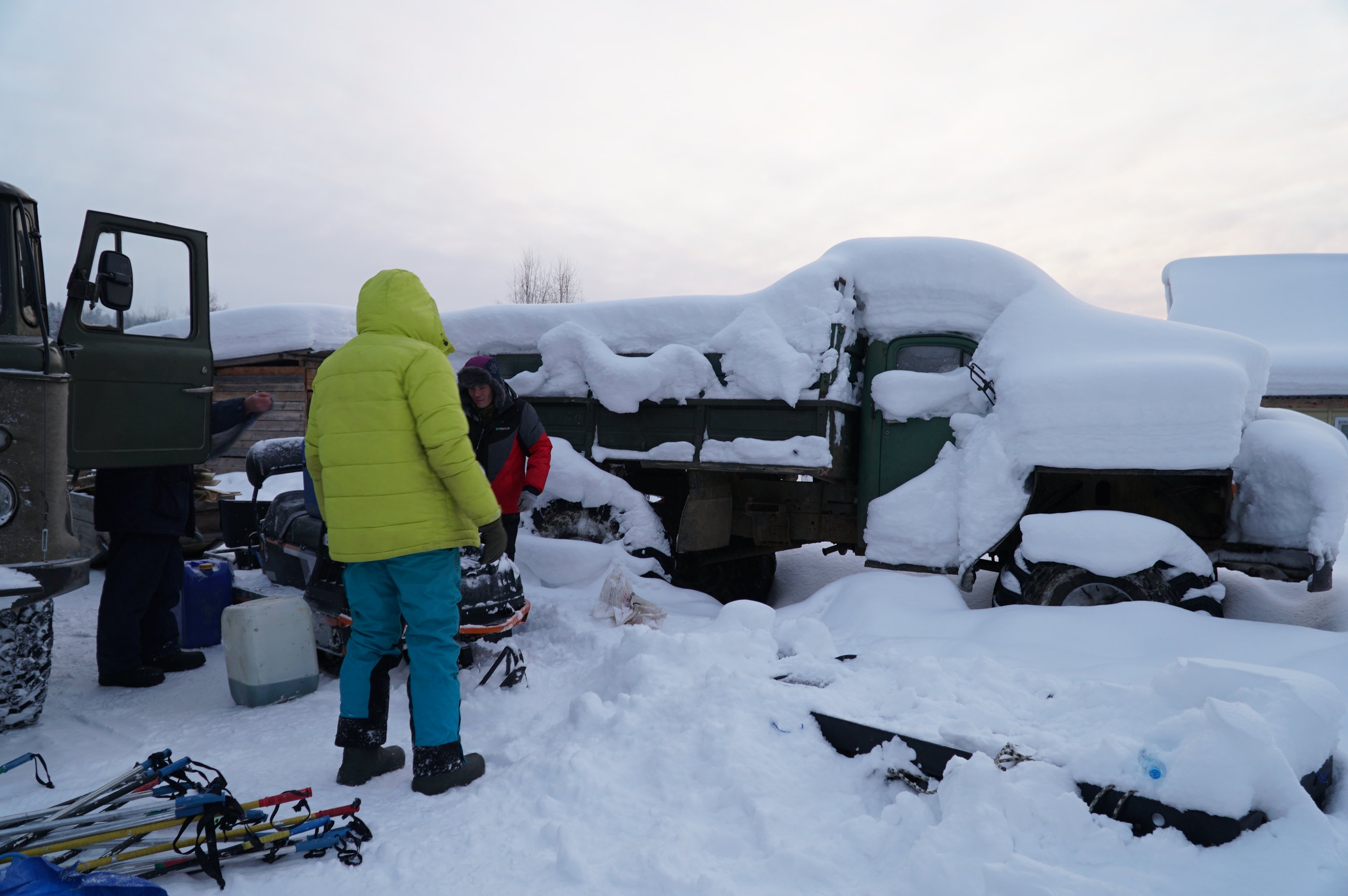 people standing by snow covered trucks and ski gear