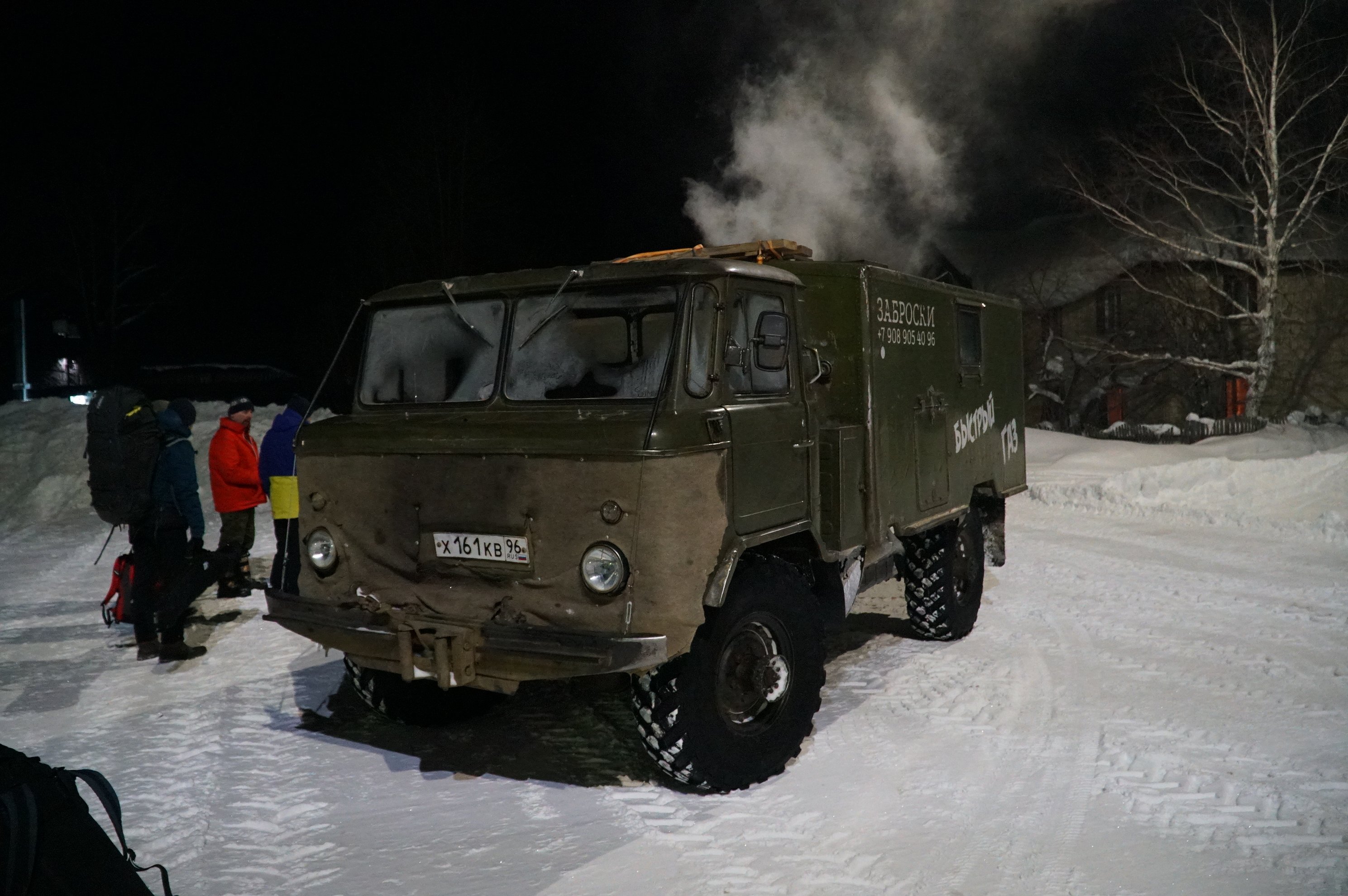 Green off-road transport truck parked in snow at night