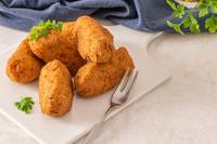 pile of fritters on white plate with fork and parsley
