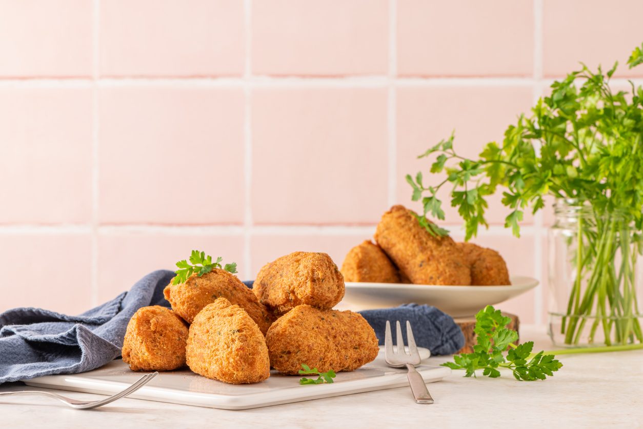Primeiro plano de bolinhos num prato branco com salsa