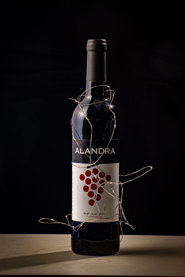 bottle wrapped in thin fairy lights against black background