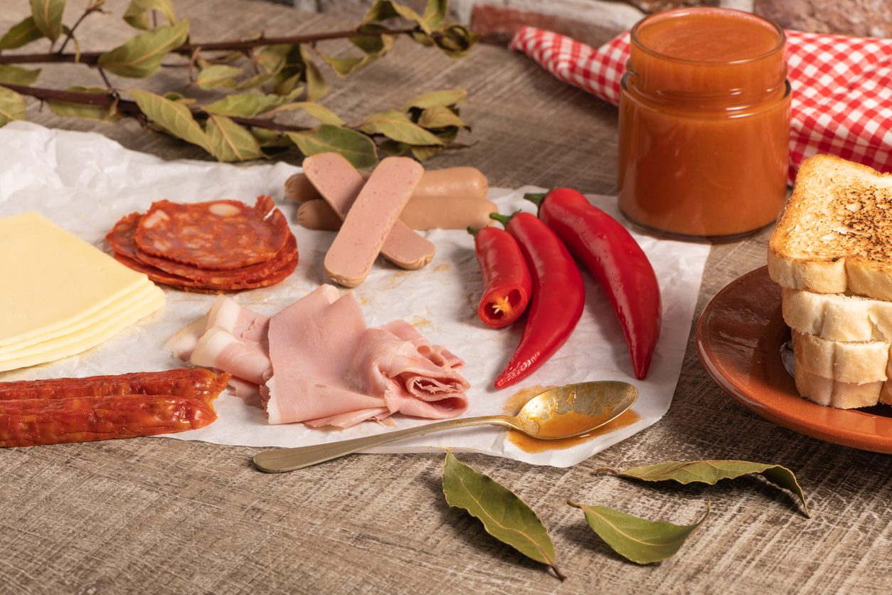 Deconstructed ingredients including sliced meats, bread, chillies, and sauce jar