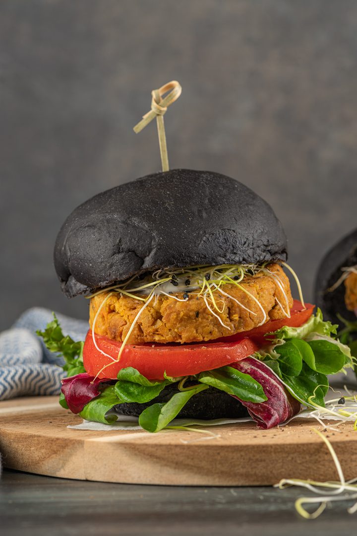 Side view of burger on wooden board with bamboo skewer