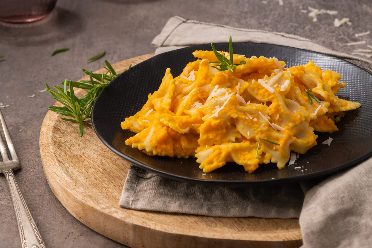 top-down angle of pasta on a black plate and wooden board
