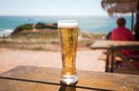 copo de cerveja numa mesa de madeira com fundo costeiro