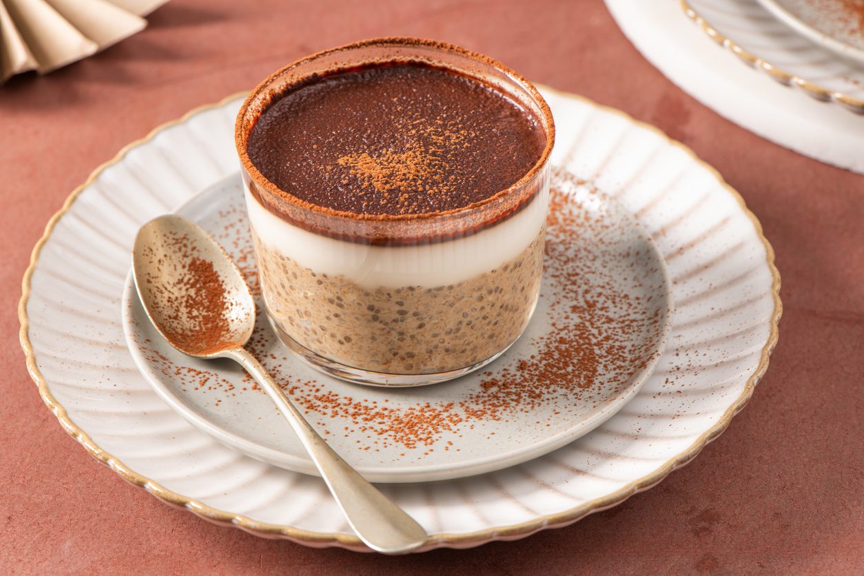 Side view of layered pudding in a glass with a spoon.