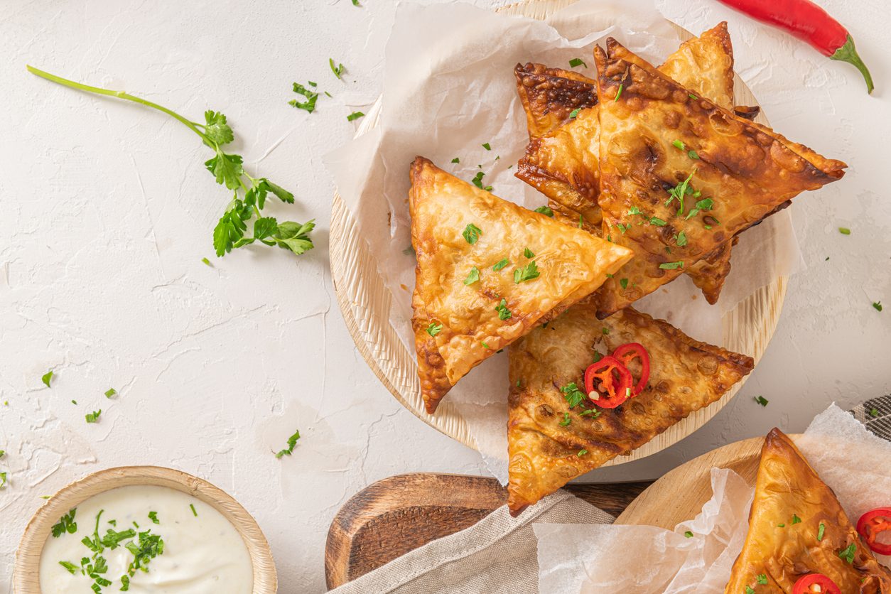 top down view of samosas on a wooden plate with dip