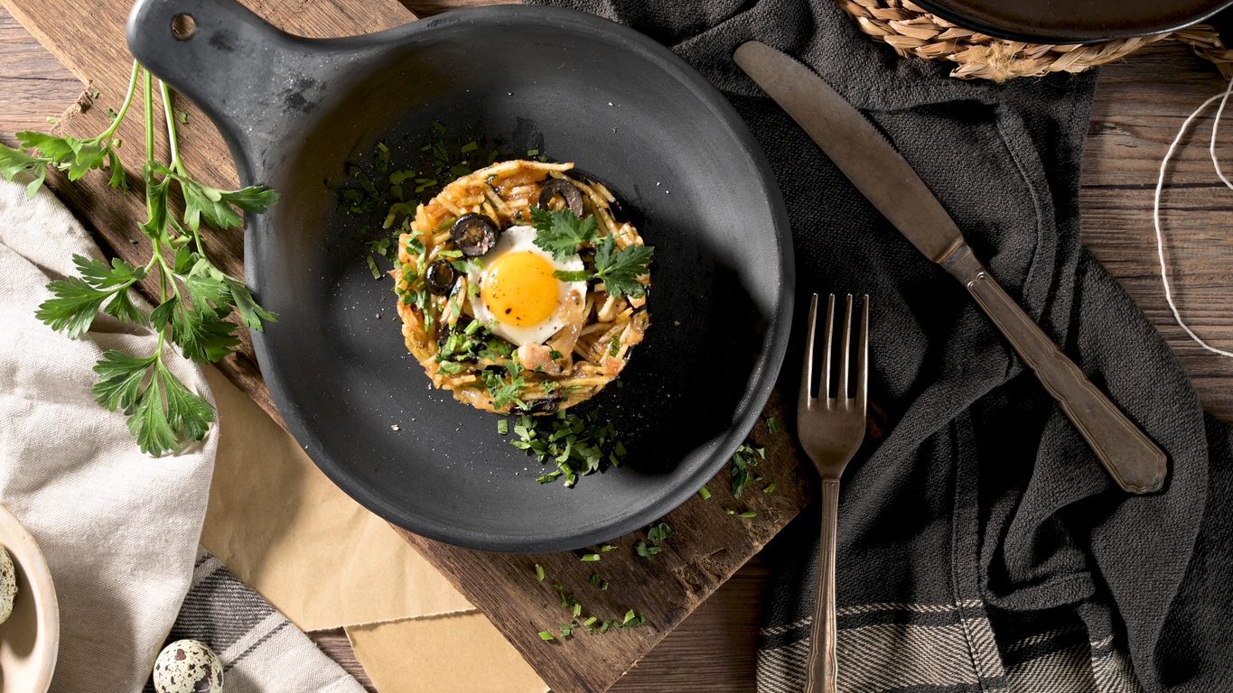 Top-down view of dish in black pan with fried egg