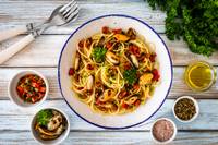 Top-down view of pasta bowl with side condiments and cutlery