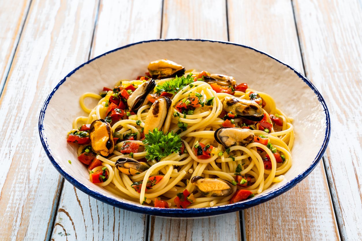 top-down view of pasta bowl on white wooden table