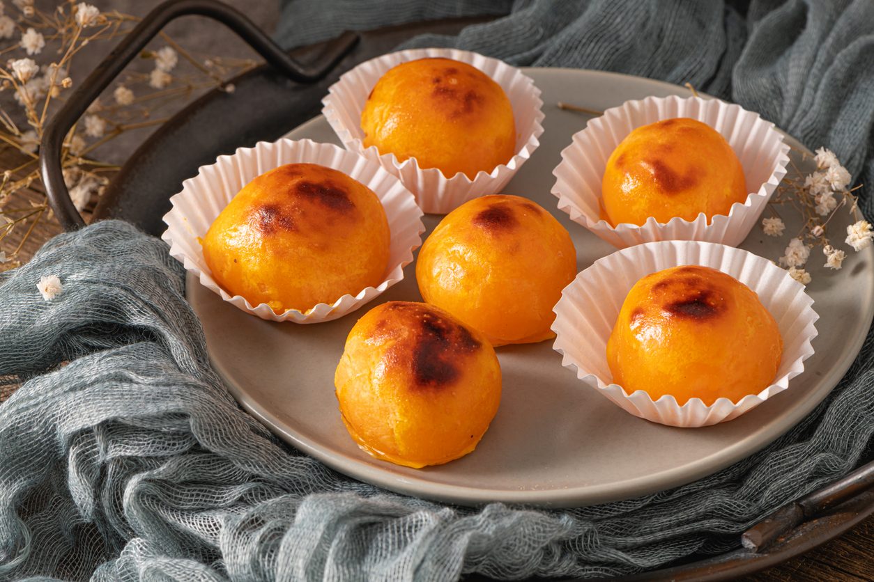 Six round sweets in paper liners on a grey plate