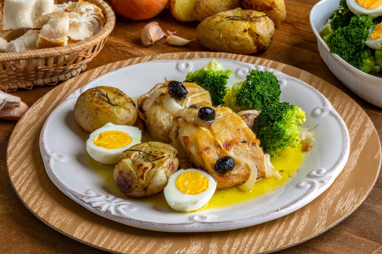 Overhead view of plated cod with sides and bread basket