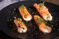 Four salmon rolls on a black plate from a high angle