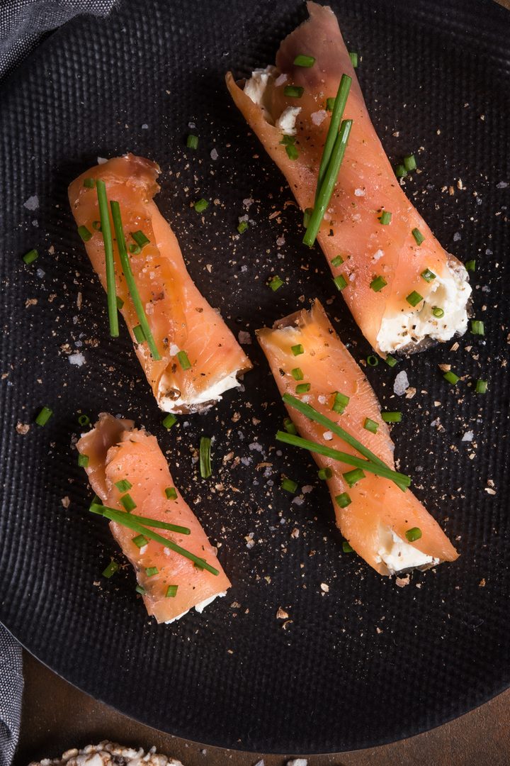 Top-down view of four salmon rolls on a black plate