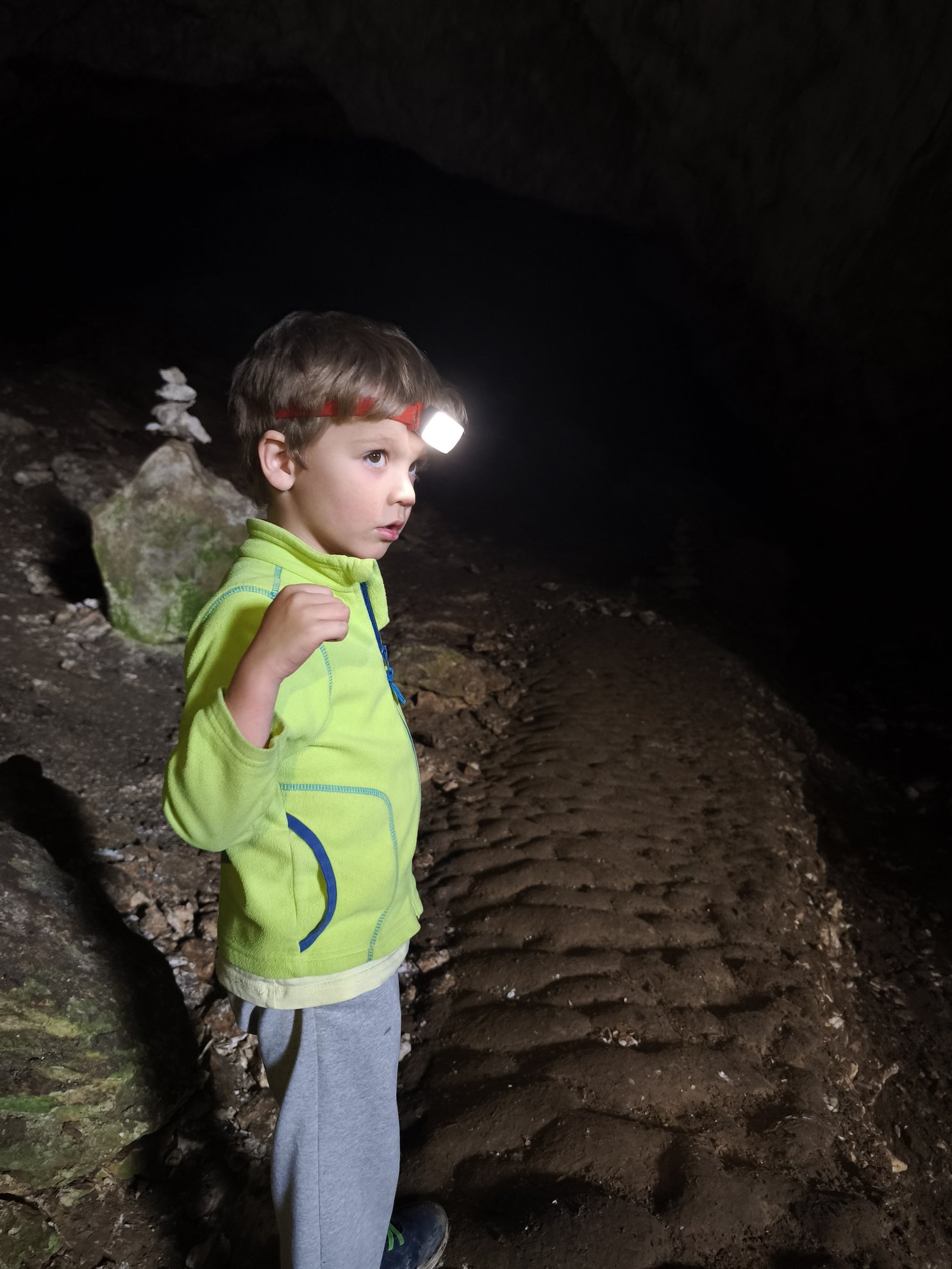 person with headlamp walking on cave floor
