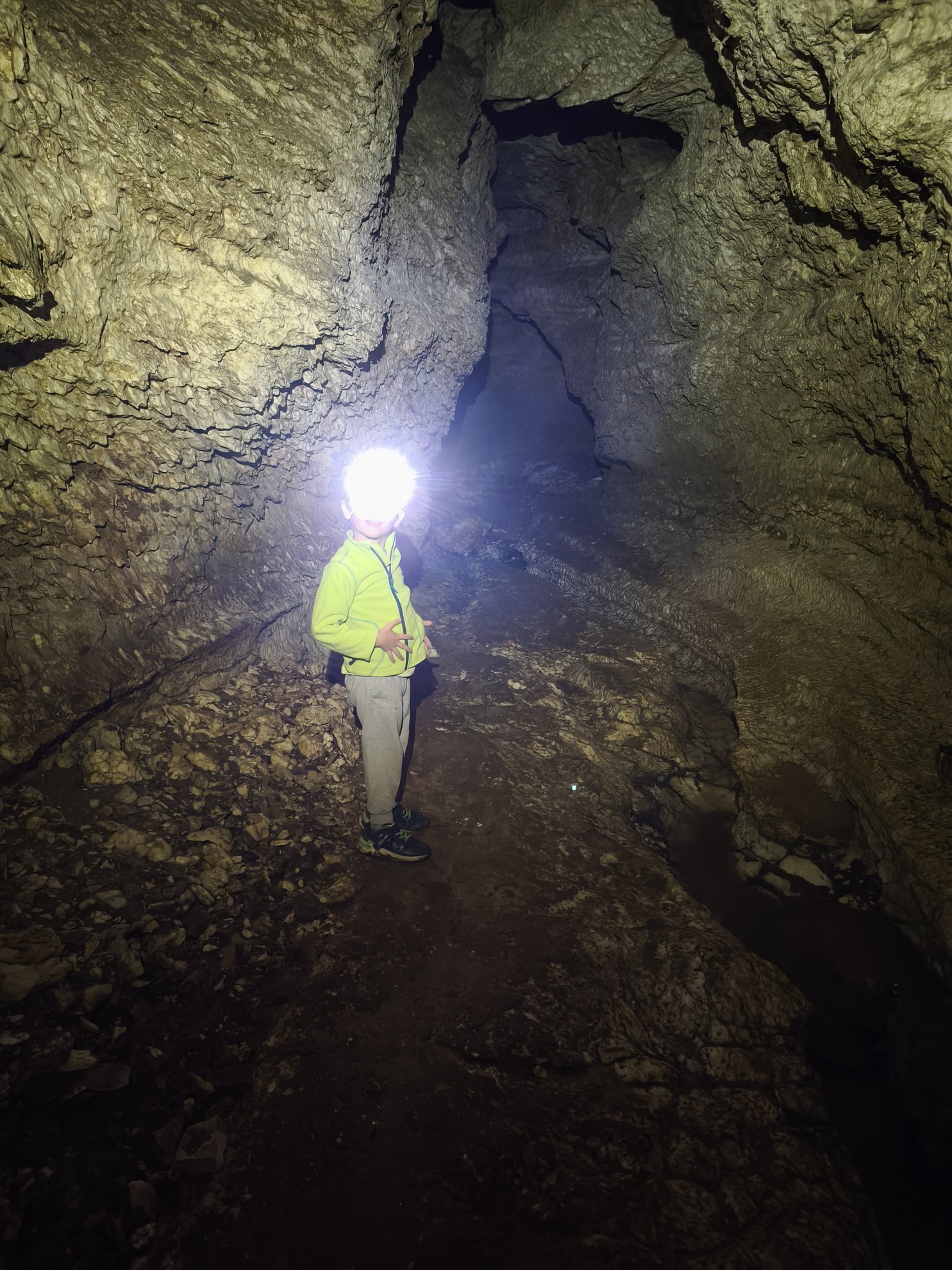 person with headlamp standing in a cave passage