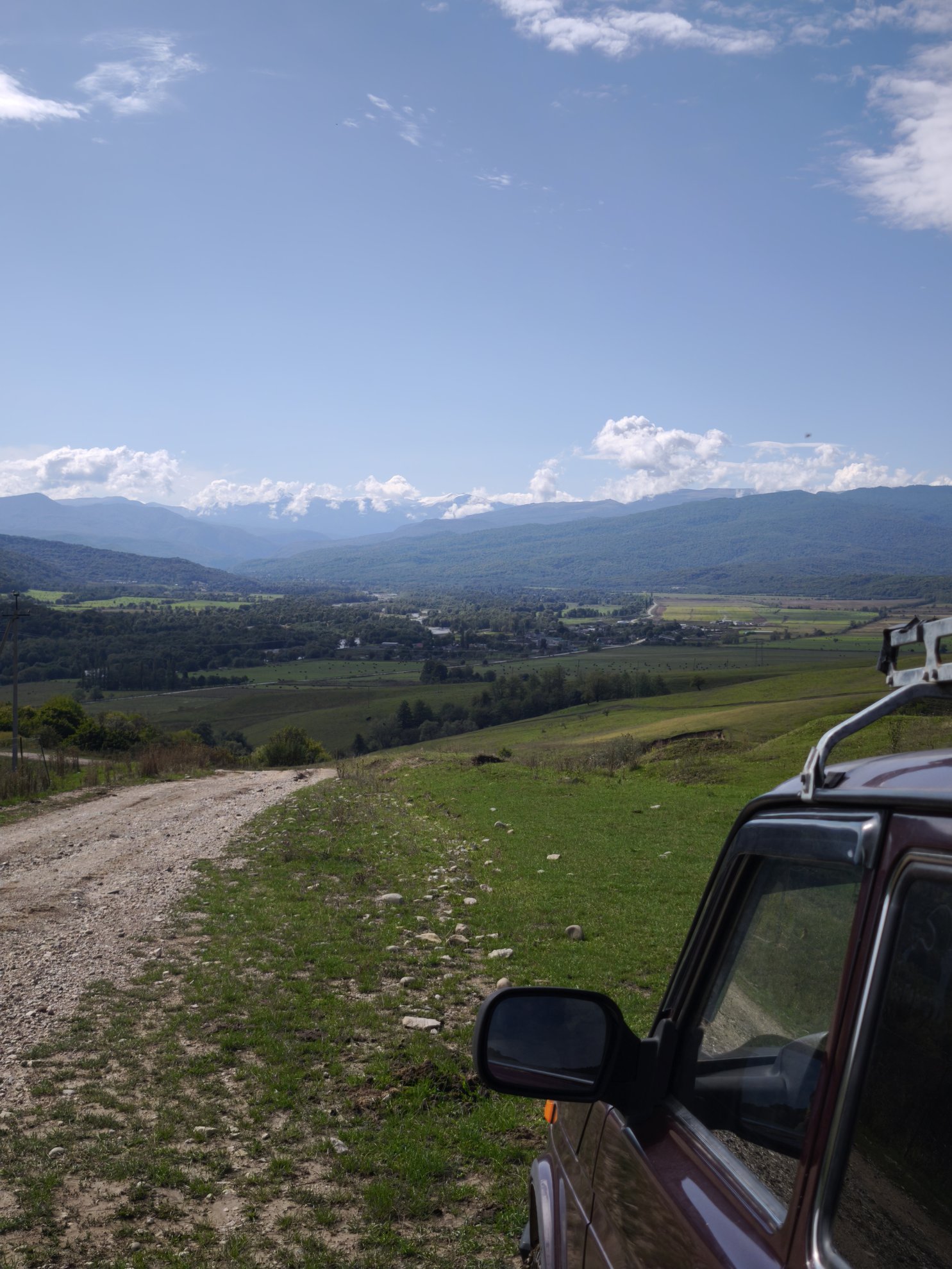 dirt road leading toward mountains with car in foreground