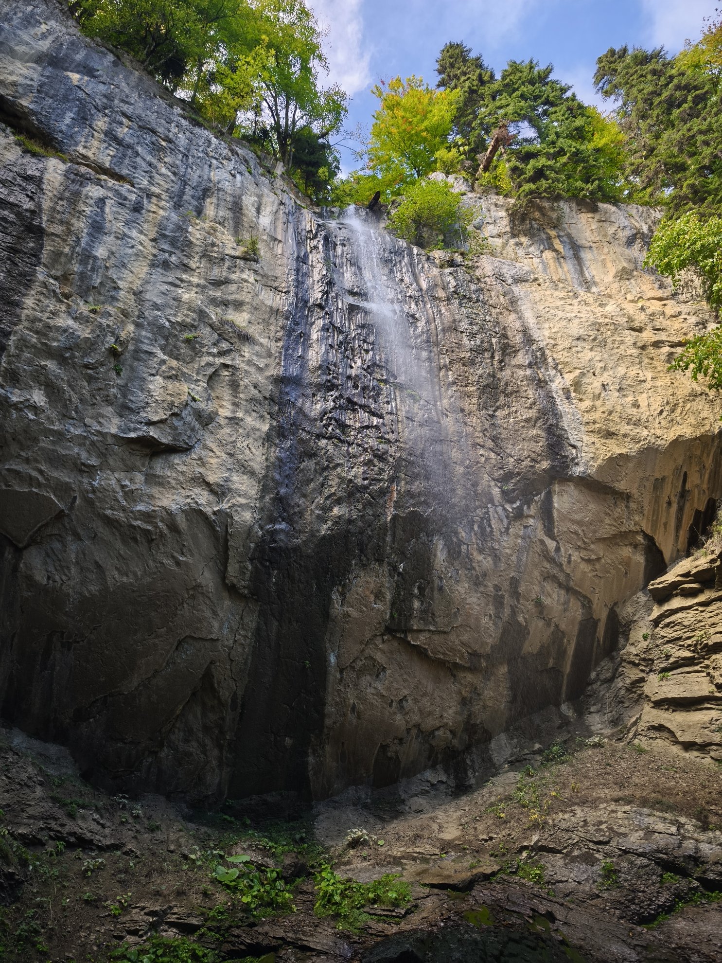 low angle view of the waterfall and rock wall