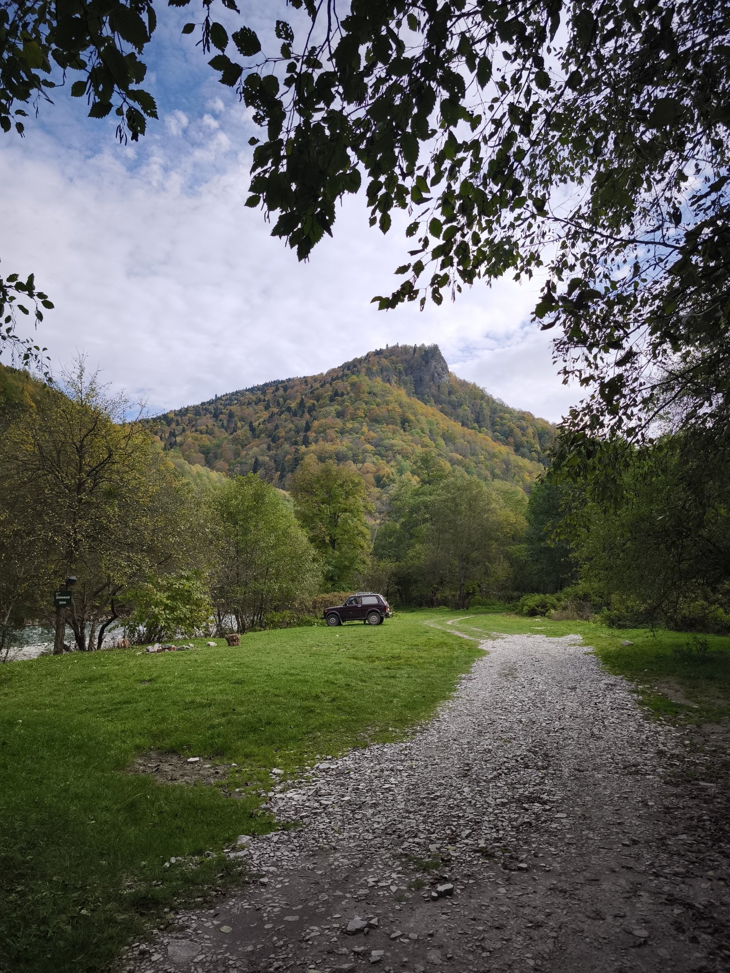 estrada de gravilha a dirigir-se a uma montanha e carro estacionado