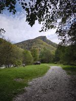 gravel road leading toward a mountain and parked car