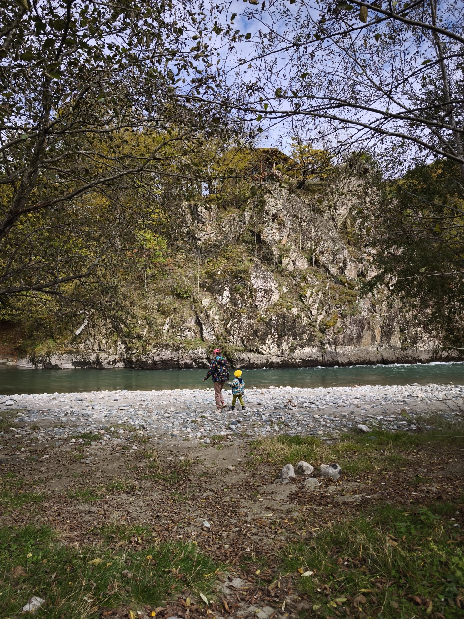 margem do rio pedregosa com uma falésia e floresta ao fundo